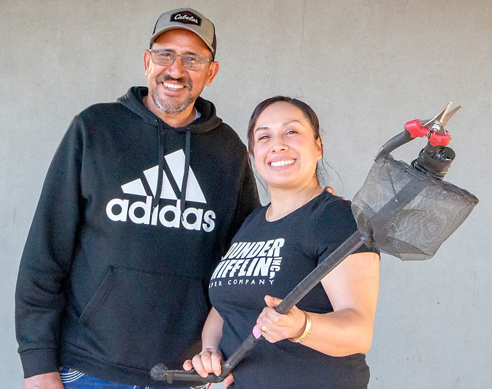 Gabriel y Patricia Oropeza, trabajadores de una huerta en Wapato, Washington, muestran sus tijeras de raleo (descuate) montadas en un poste