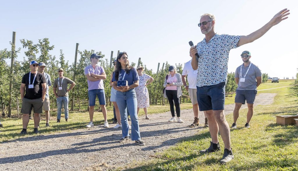 Durante la visita de la IFTA a las huertas de Ontario en julio, Michael Versteegh, a la derecha, comentó que el clima otoñal, cada vez menos predecible, ha provocado daños invernales en algunos de sus árboles. (Matt Milkovich/Good Fruit Grower)