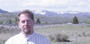 Jesse Lane stands on acreage planned by the Washington Growers League for a 126-bed project to help fill the housing needs of tree fruit seasonal workers. Stemilt Hill, near Wenatchee, Washington, is in the background.