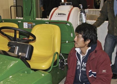 Former Washington State University scientist Dr. Michio Kise shows the multipurpose autonomous sprayer, under development by Dr. Fran Pierce, to Washington growers at a  winter grape meeting.