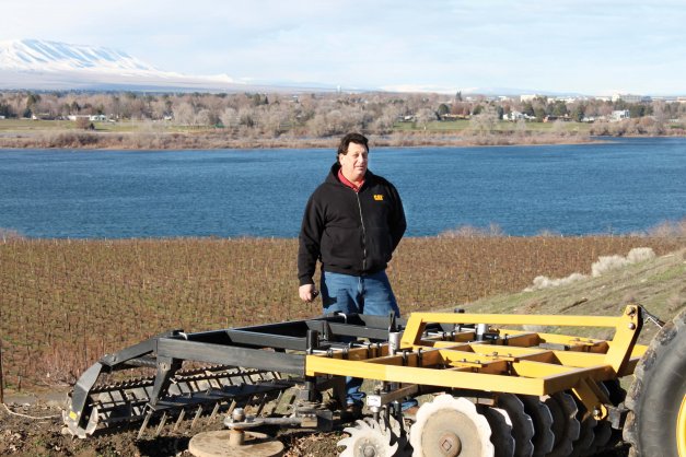 Dave Kohler stands behind soil conditioner equipment that includes the SpinWeeder he invented. The SpinWeeder (flat disk in the middle of the equipment), is manufactured by Northstar Attachments and sold by Oxbo International.