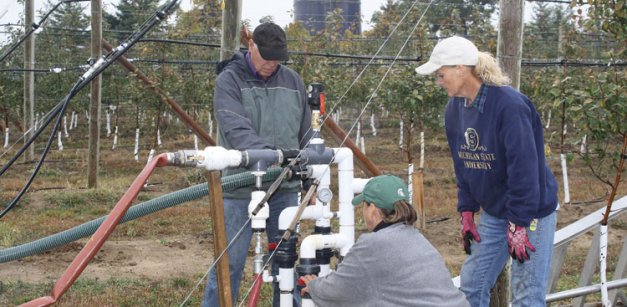 MSU horticulturist Ron Perry, left, worked with engineers to design and install the system. Here he works with two technicians.