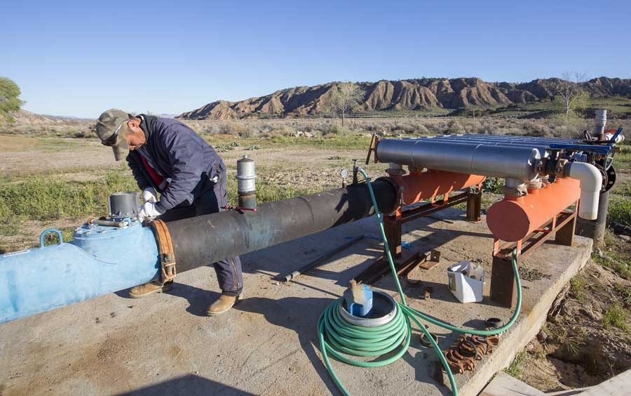 Marcel Emea repairs a seal on an irrigation pump. The orchards rely on pumped irrigation because the remote location lacks a canal system.<b srcset=
