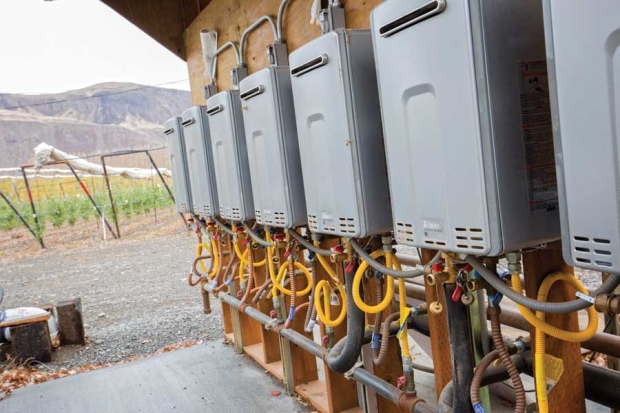 Del Feigal is experimenting with on-demand propane water heaters to artificially warm a 6-acre block of trees in late winter at Auvil Fruit Company near Vantage, Washington, on November 19, 2015. The heaters supply hot water to underground pipes beneath the apple trees in the distance. <b>(TJ Mullinax/Good Fruit Grower)</b>