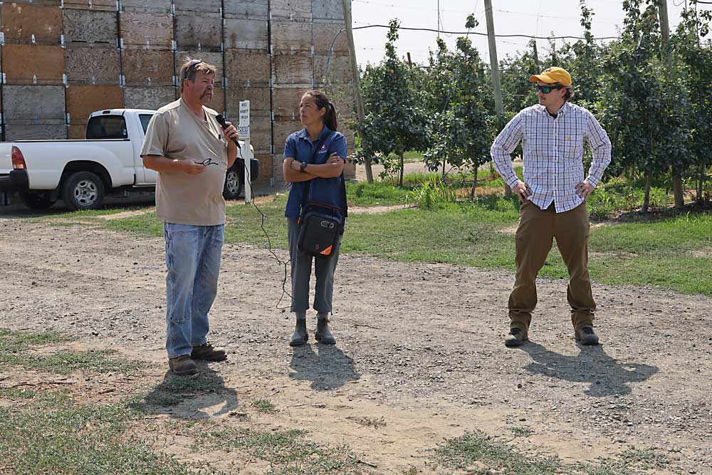 Taggares Fruit Co. horticulturist Erick Smith discusses his efforts to adjust irrigation with Bernardita Sallato of Washington State University and Andrew Bierer of the U.S. Department of Agriculture during a field day focused on irrigation technology. (Kate Prengaman/Good Fruit Grower)