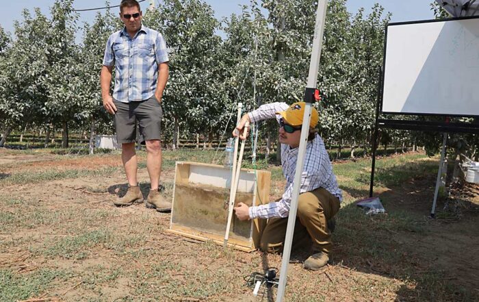Andrew Bierer, a soil scientist with the U.S. Department of Agriculture, discusses the placement of soil sensors above and below the barrier layer in the soil slice displayed in the sample box, during an irrigation technology field day organized by Washington State University in Burbank, Washington, on July 25. (Kate Prengaman/Good Fruit Grower)