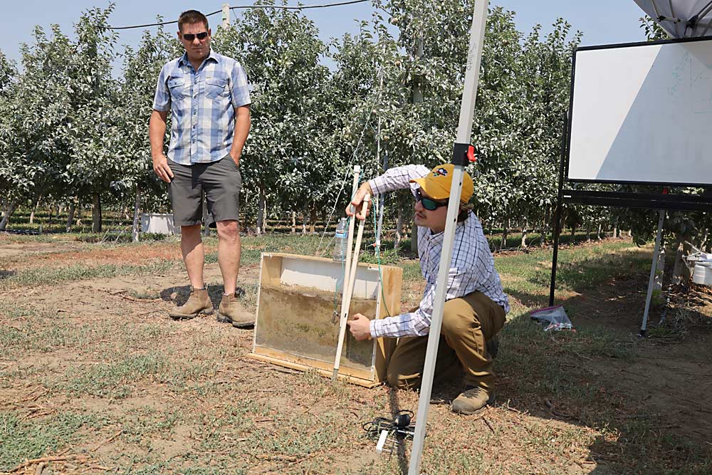 Andrew Bierer, a soil scientist with the U.S. Department of Agriculture, discusses the placement of soil sensors above and below the barrier layer in the soil slice displayed in the sample box, during an irrigation technology field day organized by Washington State University in Burbank, Washington, on July 25. (Kate Prengaman/Good Fruit Grower)