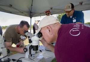 Jeff Hamrick, left, and Gareth Nisbett peer into microscopes to identify grape mealybug, which look like thrips to the naked eye, at the 2025 Washington State Grape Society field day on July 24, 2025, at Inland Desert Nursery near Benton City, Washington. (Ross Courtney/Good Fruit Grower)
