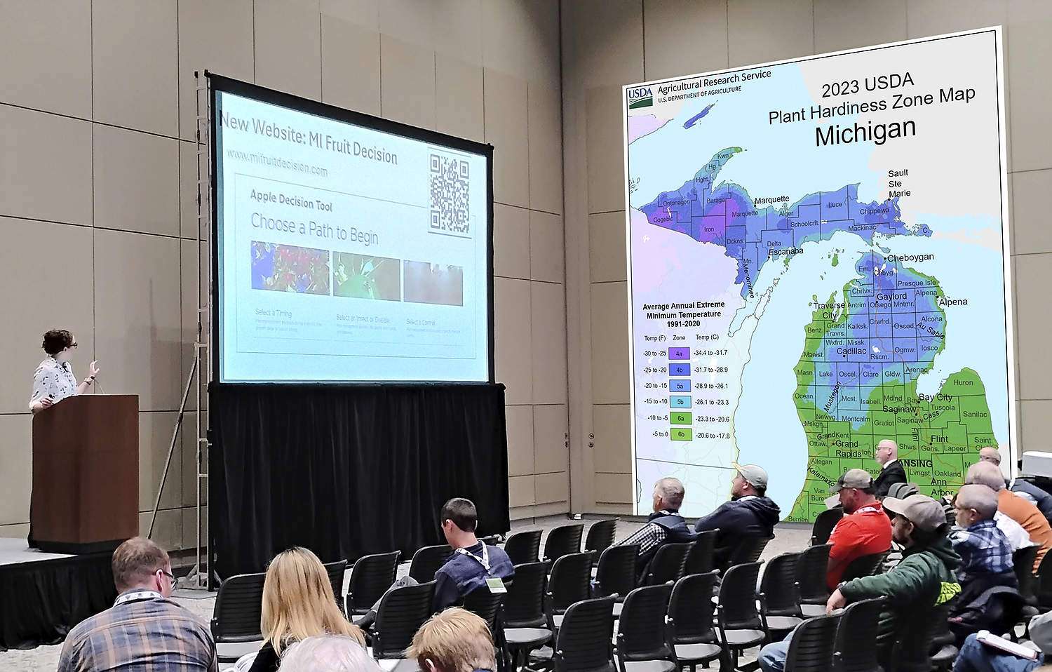 Pest control plans also shift with climate-morphosis Michigan State University tree fruit integrator Jackie Perkins discusses changing weather and pest patterns during the Great Lakes EXPO in December. Here, she was describing a new MSU website called mifruitdecision.com, which helps growers manage climate-related pest risks. On the right is an illustration of another one of her presentation slides, the 2023 USDA Plant Hardiness Zone Map of Michigan, which she used to illustrate changing climate patterns. (Photo illustration by Matt Milkovich and TJ Mullinax/Good Fruit Grower)