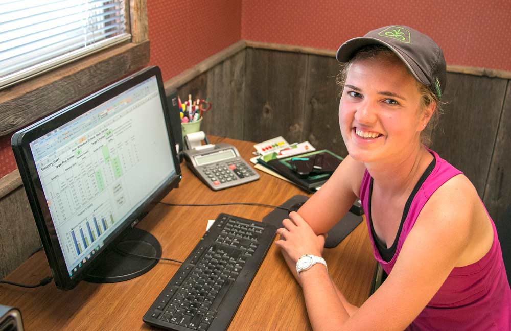Elizabeth Wittenbach shows the precision crop load management model in her family’s farm office in July in Belding, Michigan. Wittenbach uses the spreadsheet to time the farm’s chemical thinning regimen, and — if things go according to plan — avoid the more expensive chore of hand thinning. <b>(Ross Courtney/Good Fruit Grower)</b>