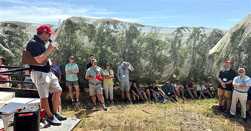 Graeme Krige, left, technical director for the Two-A-Day Group cooperative talks to International Fruit Tree Association tour attendees about the benefits of shade netting for reducing sunburn on apples and pears at Oewerzicht Farm in Greyton, South Africa. (TJ Mullinax/Good Fruit Grower)