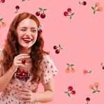 Promoters with Northwest Cherries anchored the imagery for the 2024 marketing campaign with this stock image of a redhead enjoying her cherries. They plan to reuse it in 2025, along with the pink background color. (Courtesy Northwest Cherries)