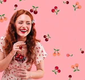 Promoters with Northwest Cherries anchored the imagery for the 2024 marketing campaign with this stock image of a redhead enjoying her cherries. They plan to reuse it in 2025, along with the pink background color. (Courtesy Northwest Cherries)