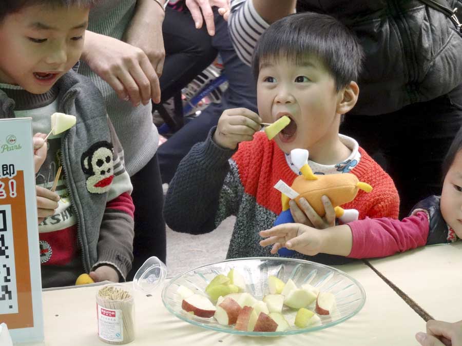 Photos courtesy of Pear Bureau Northwest A boy chomps into a pear slice at a stop in China along the USA Pear Road Show, a promotion of Pear Bureau Northwest. In a routine vote, growers in Washington and Oregon are being asked to approve continuing the marketing order that allows such generic promotions.<b> (Courtesy Pear Bureau Northwest)</b>