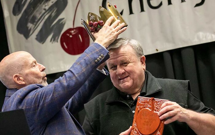 Mike Taylor, left, the 2024 Cherry King, crowns 2025 Cherry King Gary Grove. Grove retired at the end of 2024, after 38 years as a pathologist at Washington State University, where he focused on helping cherry growers manage powdery mildew. (TJ Mullinax/Good Fruit Grower)