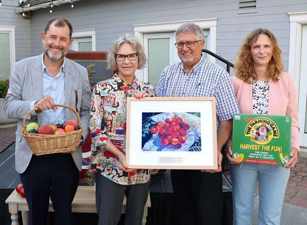Washington State University President Elizabeth Cantwell, second from left, accepts a cherry painting and other gifts...
