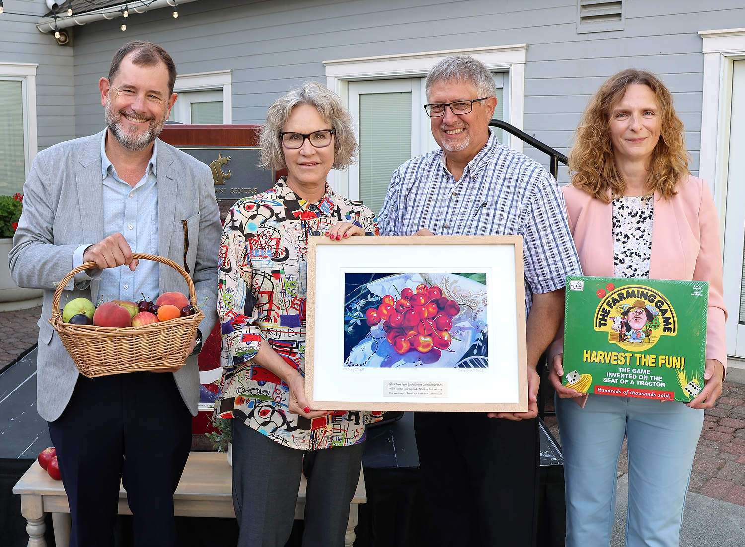 Washington State University President Elizabeth Cantwell, second from left, accepts a cherry painting and other gifts...