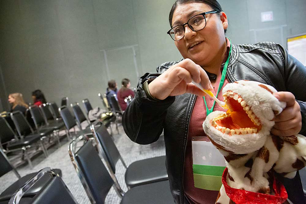 Dalia Ramirez Cruz of the Quincy Community Health Center demonstrates proper toothbrushing techniques for a small group at the Agriculture Safety Day on Feb. 5 at the Yakima Convention Center in Yakima, Washington. The event covers traditional safety issues, such as tractor operation, as well as overall mental, physical and oral health. (Ross Courtney/Good Fruit Grower)