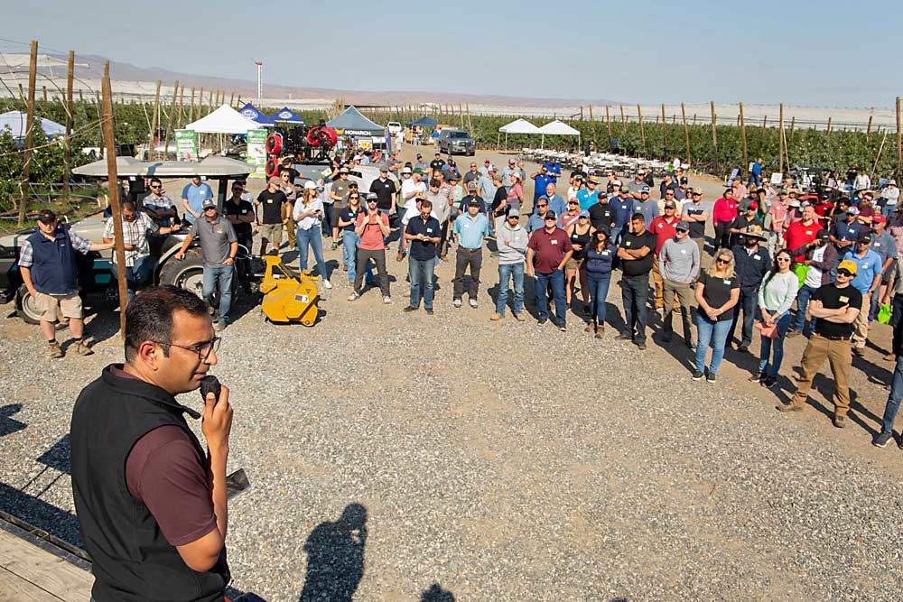 Lav Khot, left, of Washington State University greets guests on July 26 at the Smart Orchard field day in Mattawa. About 200 people attended the event that showcased the high-tech tools of more than 20 vendors. (Ross Courtney/Good Fruit Grower)