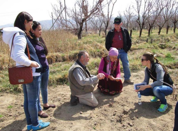 Raisa Tologonova discusses fruit growing in Kyrgyzstan with Cashmere, Washington orchardists Jim Koempel (crouching) and Randy Smith (standing). Tologonova’s daughters are on the left and interpreter Olga Kuticheva is on the right. <b>(Courtesy Randy Smith)</b>