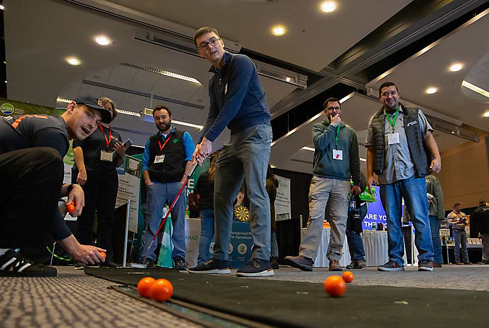 Brian McDarment of CliftonLarsonAllen draws a crowd as he putts at a trade show booth on Monday afternoon at the Yakima Convention Center. Most of the trade show, however, takes place at the nearby Yakima Valley SunDome. (Ross Courtney/Good Fruit Grower)