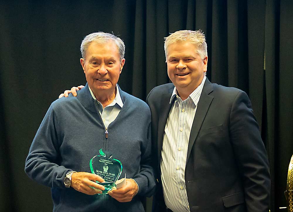 Bill Zirkle, left, receives the Silver Apple Award on Dec. 10 from Jeff Baldwin at the Washington State Tree Fruit Association Annual Meeting awards banquet at the Yakima Convention Center. (Ross Courtney/Good Fruit Grower)