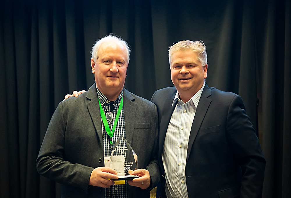 Ed Ing, left, receives the Silver Pear Award on Dec. 10 from Jeff Baldwin at the Washington State Tree Fruit Association Annual Meeting awards banquet at the Yakima Convention Center. (Ross Courtney/Good Fruit Grower)