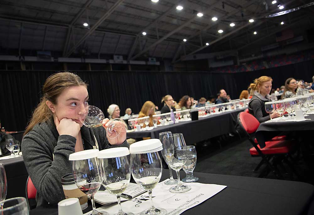 Grace Fenner of Bayernmoor Cellars tests the aroma of a white wine while listening to a panel of speakers discuss Washington’s classic cultivars — many white — and their potential in today’s market during the WineVit Grand Tasting in Kennewick, Washington, in February. Five of the six wines on the table setting were white. (Ross Courtney/Good Fruit Grower)