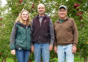 Three generations of Wittenbachs — Elizabeth, her father, Mike, and her grandfather, Ed — pause in the test plot, which includes seven new varieties from Washington. Elizabeth is particularly intrigued by newly released cultivars and looks forward to seeing how well the options fare in the orchard. (By Leslie Mertz)