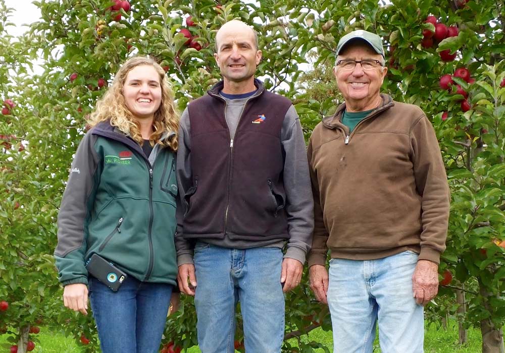 Three generations of Wittenbachs — Elizabeth, her father, Mike, and her grandfather, Ed — pause in the test plot, which includes seven new varieties from Washington. Elizabeth is particularly intrigued by newly released cultivars and looks forward to seeing how well the options fare in the orchard. <b>(By Leslie Mertz)</b>