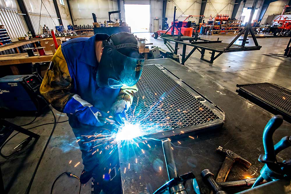 Juan Arroyo welds a steel grate onto a standing platform at the Automated Ag Systems factory in Moses Lake, Washington, last June. Automated Ag’s president and founder J.J. Dagorret says he’s had to make some changes with orders and vendors because of the volatility in the steel market. (TJ Mullinax/Good Fruit Grower)