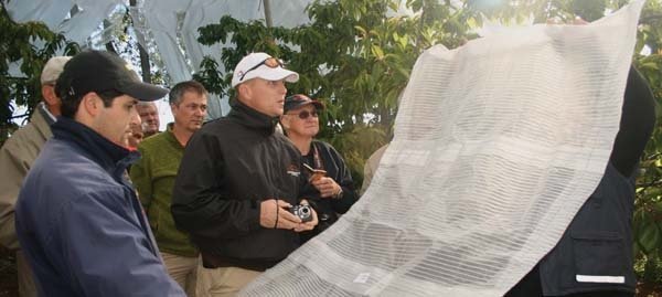 Iuar Iraira (foreground), manager of the Fundo Agua Buena orchard (in the center picture), discusses the Voen louvered rain cover with international visitors. The area, south of Temuco, receives more than 70 inches of rainfall annually.