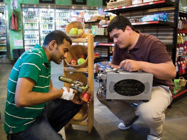 Purdue University graduate student Santosh Soparawalla, left, and postdoctoral researcher Fatkhulla Tadjimukhamedov demonstrate a miniature mass spectrometer used to detect chemicals on store produce.