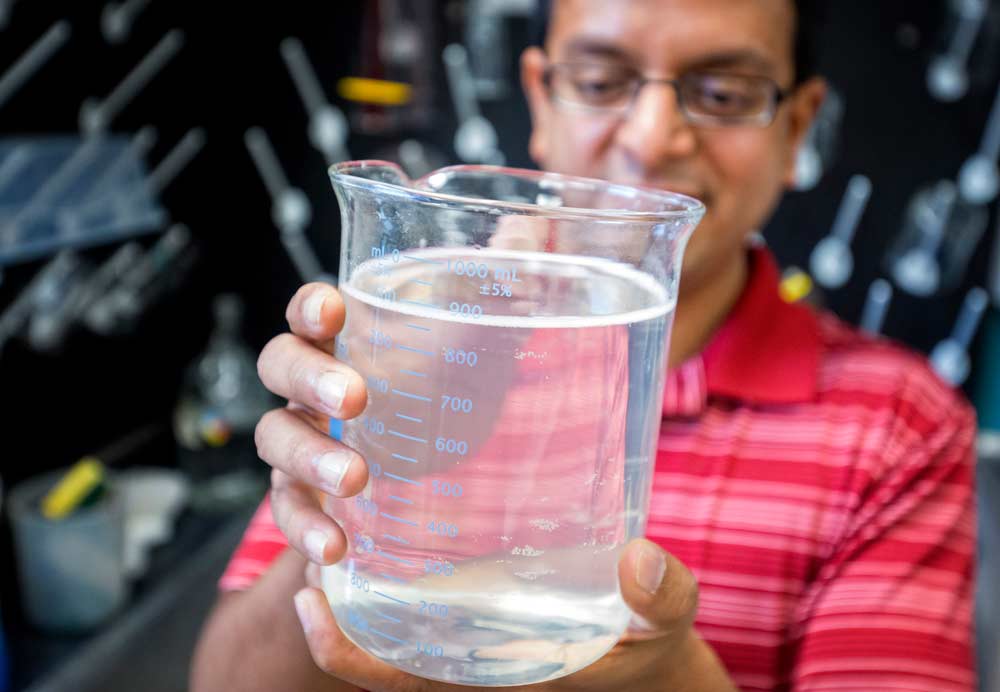 Washington State University researcher Girish Ganjyal holds a beaker containing a solution of water and Gum Acacia Senegal in his laboratory in Pullman, Washington on October, 20, 2017. Gum Acacia Senegal, a commercially available edible coating, is showing the most promise in trials to reduce cherry cracking. (TJ Mullinax/Good Fruit Grower)