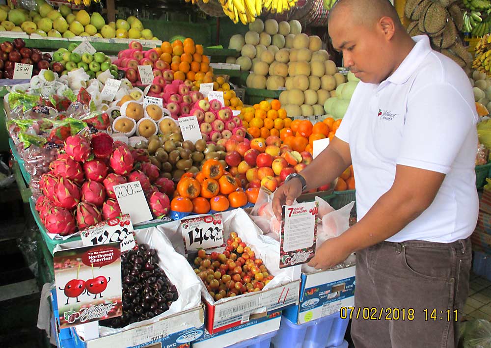 Edison Sarmiento, a merchandiser for Northwest Cherries, sets up a display at a farmers’ market in July 2018 in Quezon City, Philippines. Northwest Cherries is testing out the market for sweet cherries in the Philippines and two other Southeast Asian countries. (Courtesy Northwest Cherries)