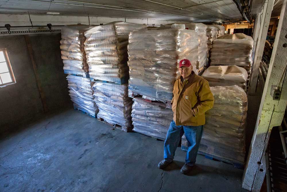 Eric Olson leans against several pallets of granulated sugar at his Naches, Washington, storage facility. Olson uses 45,000 pounds of sugar, mixed with water and sprayed on the cherries before harvest, to keep starlings and other area birds from eating his valuable crop. The sugar is purchased from Costco and delivered by tractor-trailer. <b>(TJ Mullinax/Good Fruit Grower)</b>