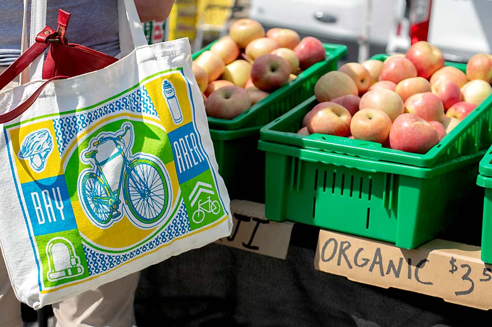 A San Francisco shopper checks out the organic Fujis at the Chinchiolo family’s Ferry Plaza Farmers Market stand. (TJ Mullinax/Good Fruit Grower)