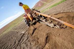 Felix Schuhmann, a student from Germany who interned with Hanrahan Orchards and the Washington Tree Fruit Research Commission in 2017, trenches for irrigation lines in preparation for a Cosmic Crisp planting in Zillah, Washington. Schuhmann is one of over 100 interns hosted by the research commission or on the Hanrahan family farm, through a mentorship program inspired by personal experience, said Ines Hanrahan, executive director of the research commission. (TJ Mullinax/Good Fruit Grower)
