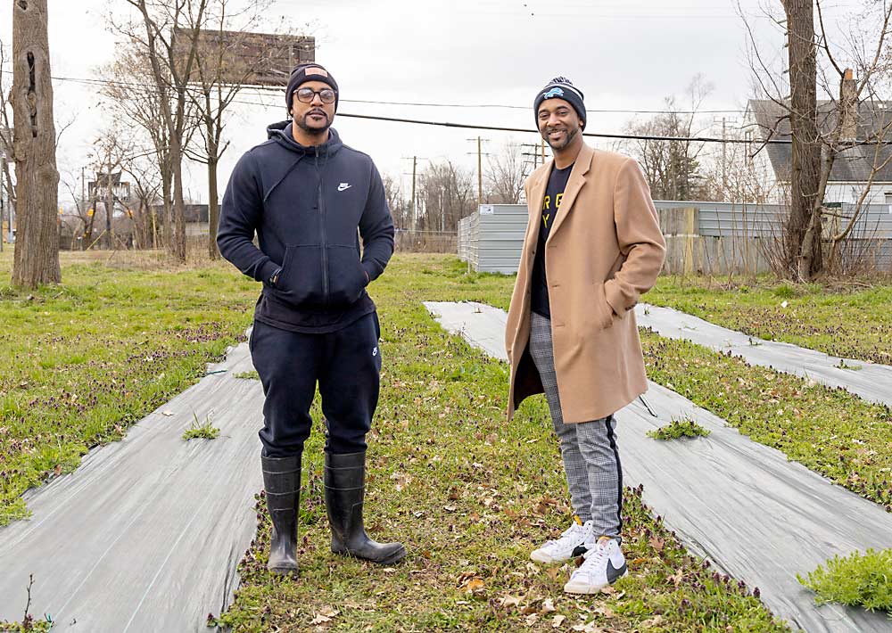 Peter King, left, and Matthew Jones, two of the partners in Drew Ryan Wines, stand among three rows of Pinot Noir vines on the northeast side of Detroit in April. From these “humble beginnings,” they plan to start their own winery and vineyard.(Matt Milkovich/Good Fruit Grower)