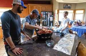 From left, Matt Eddie, his grandfather Jim Eddie and his daughter Sarah make popcorn balls together in December, while his wife, Leah, and daughters Sadie and Faith work at the table in the background. The Eddies sold their Grandview, Washington, farm last year after economic challenges pushed Eddie to thoughts of suicide. After seeking help, he now wants other growers to know their mental health matters. (TJ Mullinax/Good Fruit Grower)