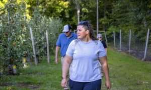 Kristen DeMarree walks along a block of Minneiska (marketed as SweeTango) during September harvest, with her parents in the background.