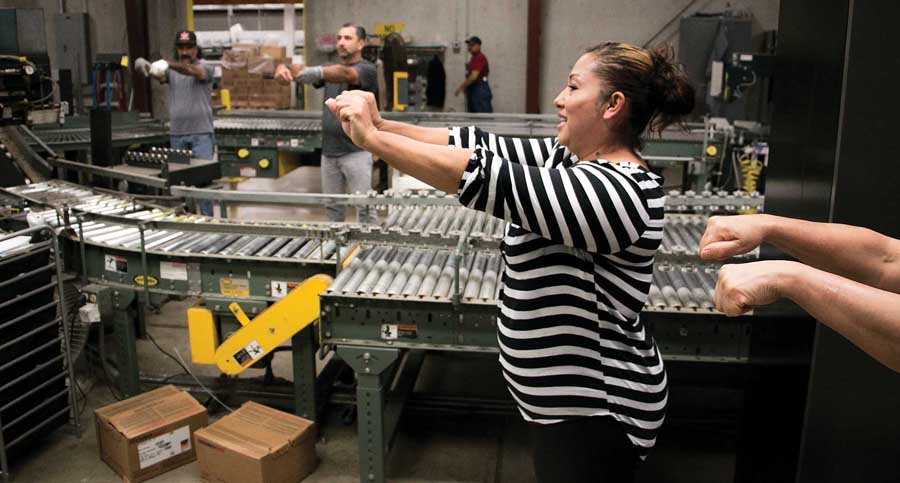 Maria Hernandez leads the 4 p.m. packing line stretching excersize before the start of the night shift at Duckwall Fruit facility in Odell, Oregon on August 21, 2014. In an effort to cut down on repetitive motion injuries, Duckwall brings in a physical therapist once a week for employe wellness checks and message therapy.