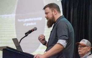 Matt Yeager of Kragworks discusses the use of large language model-based artificial intelligence in farming, while his father, Joel, watches at the Washington State Tree Fruit Association Annual Meeting in December in Wenatchee, Washington. The family uses the Claude chatbot on their own Yakima Valley farm. (TJ Mullinax/Good Fruit Grower)