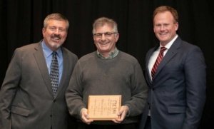 Mike Willett, center, receives the Distinguished Service Award during the Washington State Tree Fruit Association's award banquet on Tuesday, December 4, 2018, at the Yakima Convention Center in Yakima, Washington. (TJ Mullinax/Good Fruit Grower)