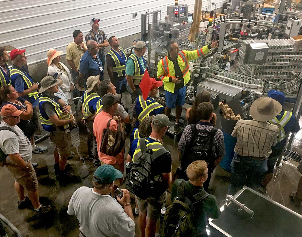 Michael Daley, general manager of the BC Tree Fruits Cider Co., explains the workings of the Kelowna, cidery, including the canning line, during the International Fruit Tree Association's summer tour in British Columbia. (Ross Courtney/Good Fruit Grower)