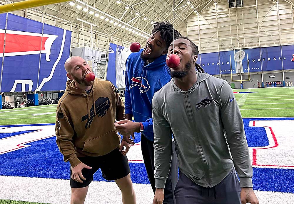 From left, Buffalo Bills football players Reid Ferguson, Greg Rousseau and James Cook bob for SnapDragon apples at the Bills training facility last November. SnapDragon is the official apple of the Buffalo Bills. (Courtesy Crunch Time Apple Growers)