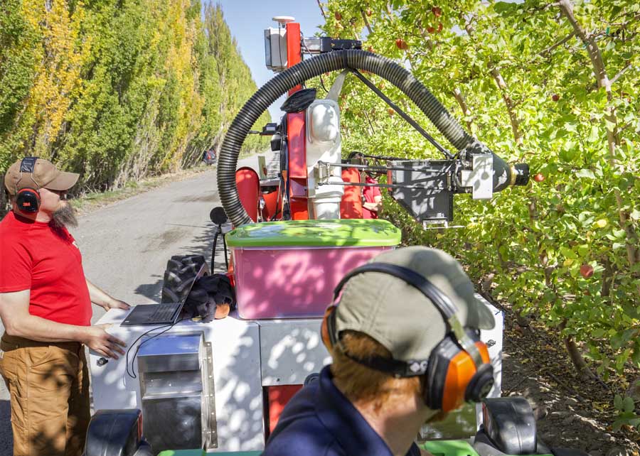 Operators of an Abundant Robotics automated vacuum harvester monitor the test vehicle working a Fuji apple block during the 2016 Washington apple harvest. (TJ Mullinax/Good Fruit Grower)