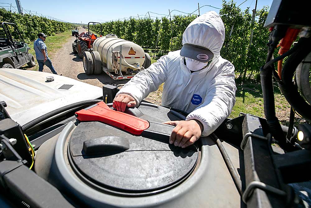 Jonathan Hernandez tops off one of Stemilt's two operational Prospr spray machines using a nurse rig that kept both autonomous sprayers filled that day. (TJ Mullinax/Good Fruit Grower)