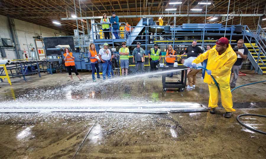 Andre Harrell evenly coats floor drains with chlorine foam before scrubbing debris off surfaces during a cleaning and sanitation workshop held by WSTFA at a Yakima valley packing house in July. (TJ Mullinax/Good Fruit Grower)