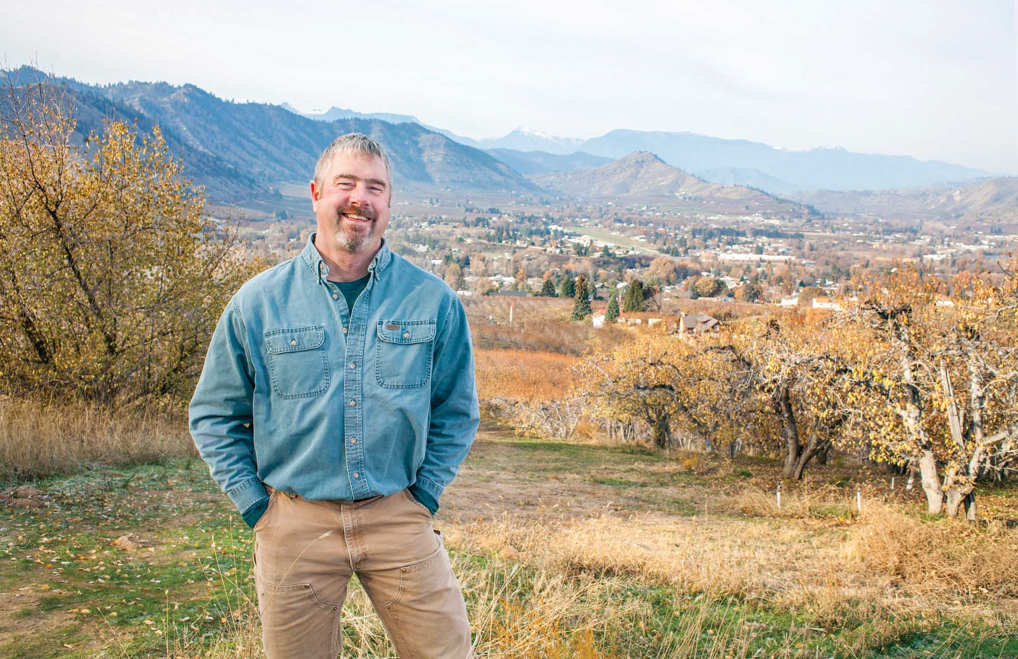 Pear grower, Ray Schmitten overlooking Cashmere, Washington in 2014. Through his childhood, Schmitten would walk this orchard row to get to school at the bottom of the hill in downtown Cashmere. (TJ Mullinax/Good Fruit Grower)